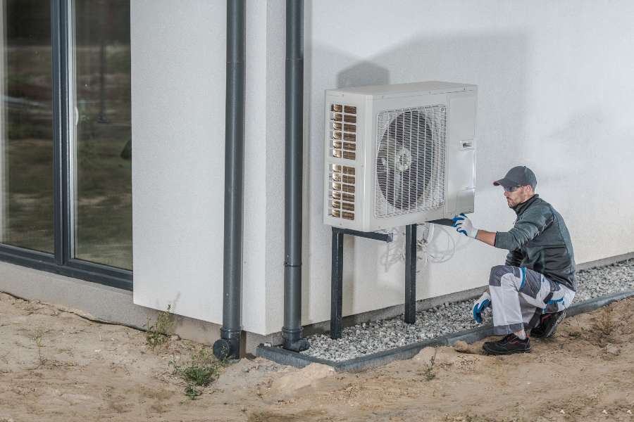 man fixing heat pump outside of home